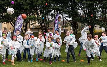 Kids in mad science lab coats throwing colored balls