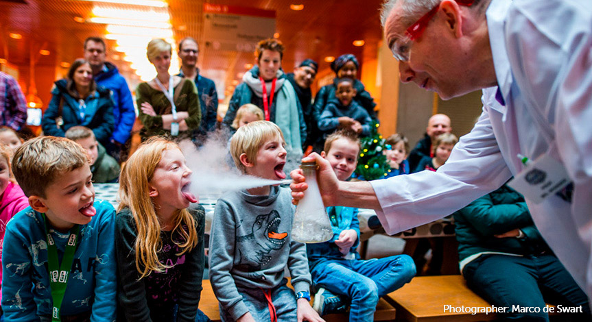 Mad scientist directing smoke from a beaker into a girls mouth
