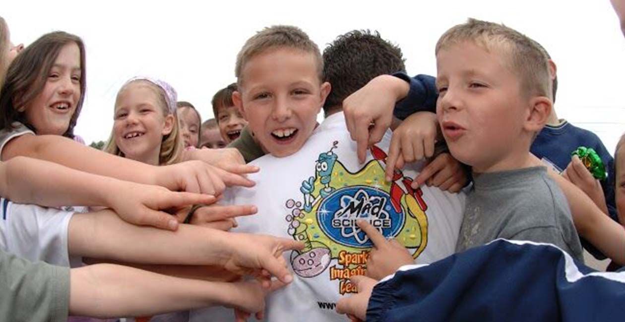 Kids pointing at their mad scientists lab coats mad science logo