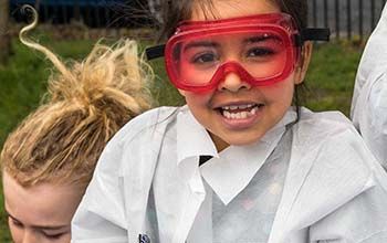 Girl in red safety goggles and a mad science lab coat